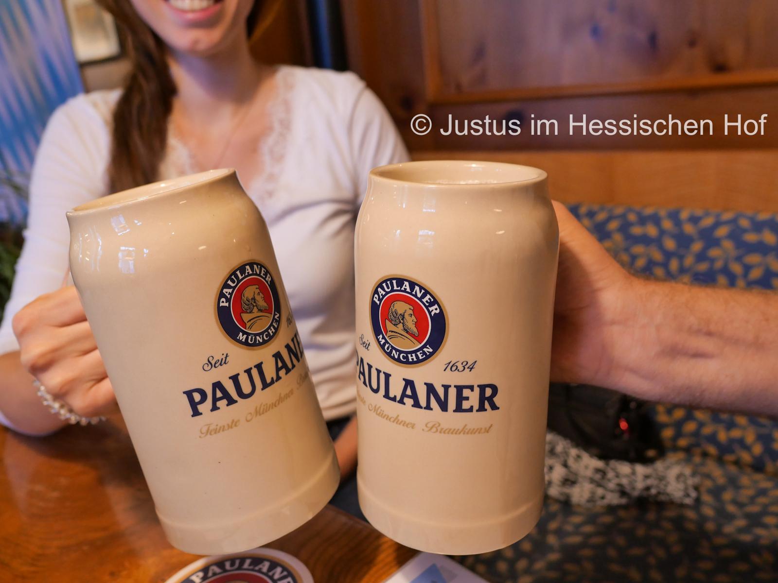 Zwei Paulaner Bierkrüge stoßen im Gasthaus Justus an
